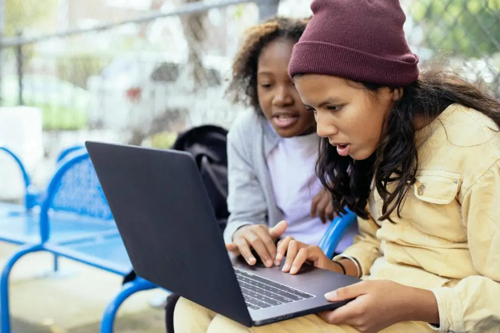 two teenagers looking shocked at a laptop screen