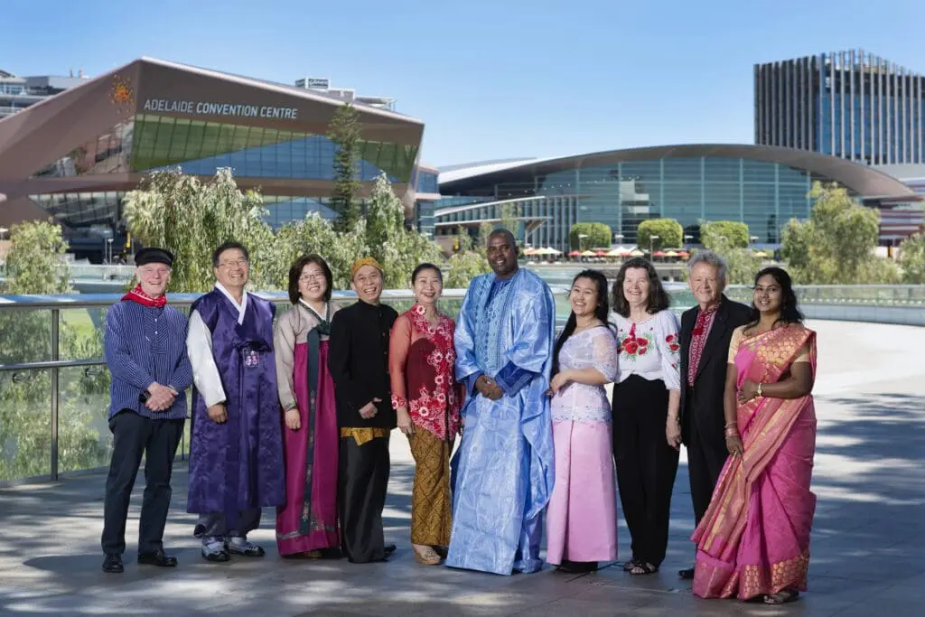 group of people in cultural dress in front of iconic SA buildings