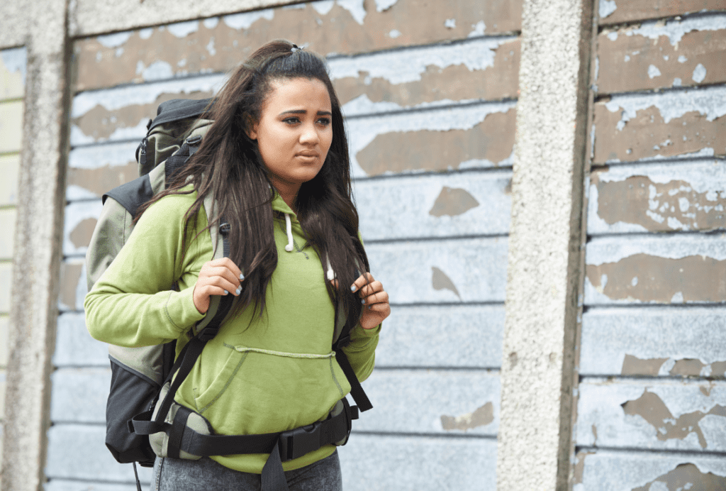 teenage woman walking with large backpack, looking uncertain