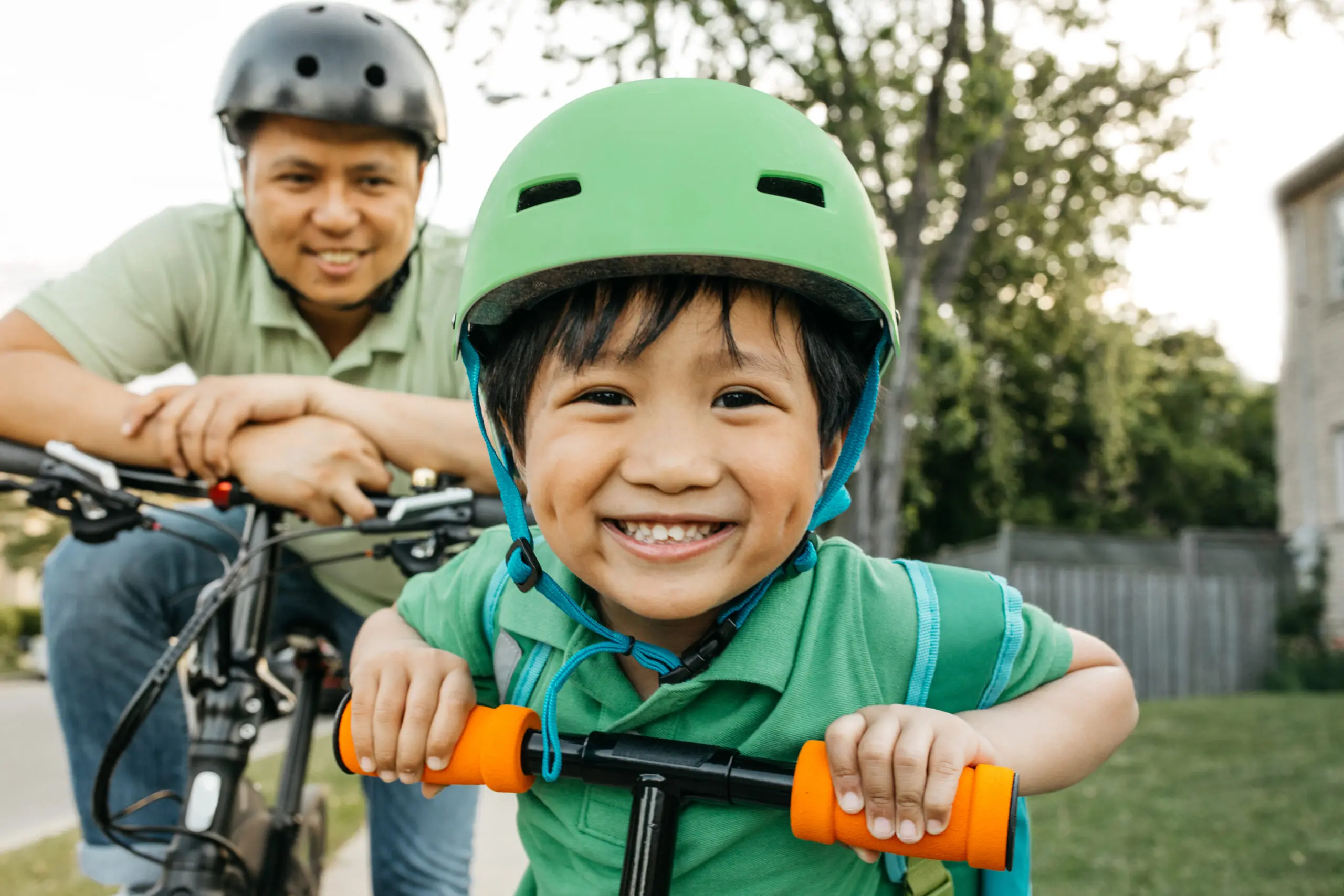 A smiling boy in a bike helmet out riding with his father
